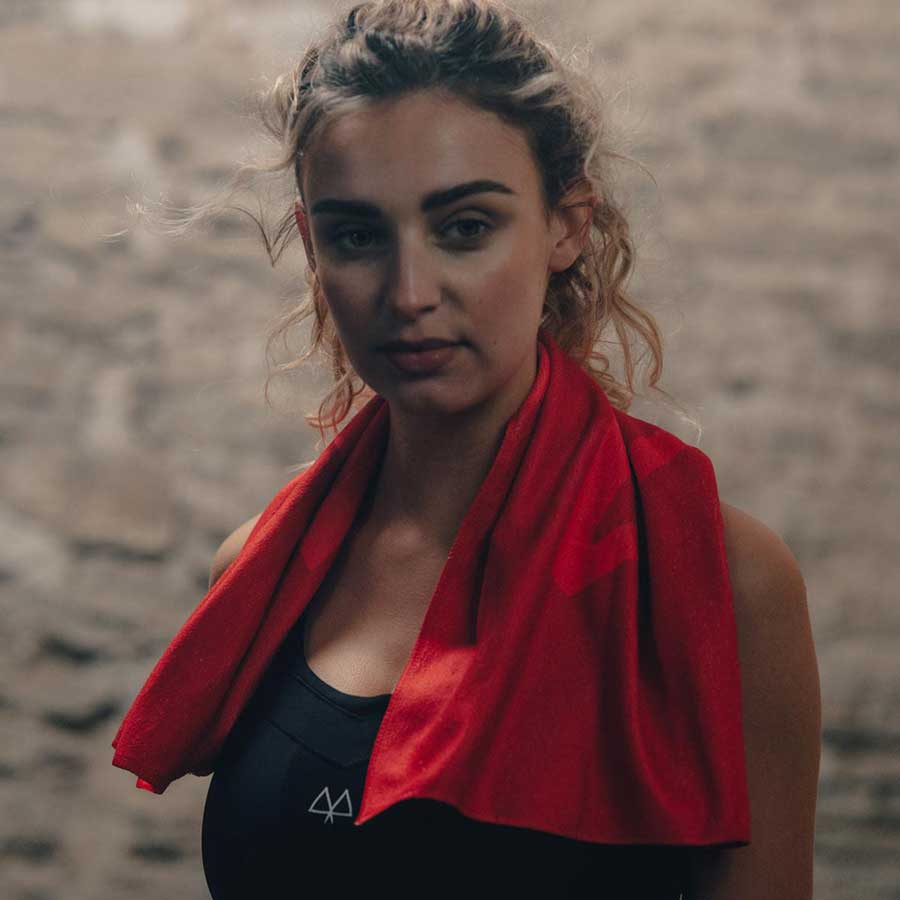 Izzy wearing the MAAREE High-Impact Solidarity Sports Bra in Black with a Red Gym Workout Towel around her Shoulders